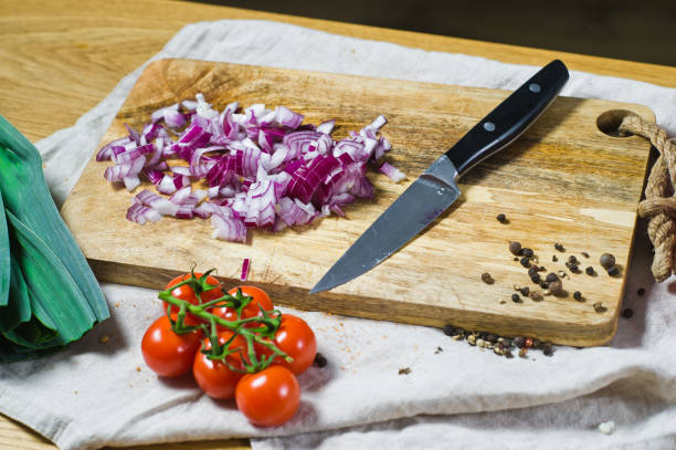 istock The chef cuts red onions on a wooden chopping Board. Background kitchen, side view. 1129464573
