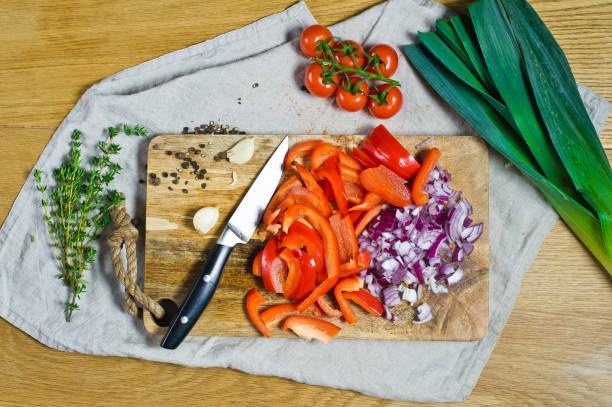 istock Cut red bell peppers and onions on a wooden chopping Board. Background kitchen, side view. 1129464635