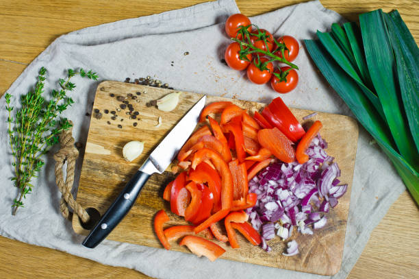 istock Cut red bell peppers and onions on a wooden chopping Board. Background kitchen, side view. 1129464653