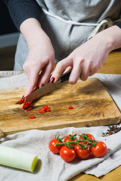 istock The chef cuts chili peppers on a wooden chopping Board. Background kitchen 1129465659