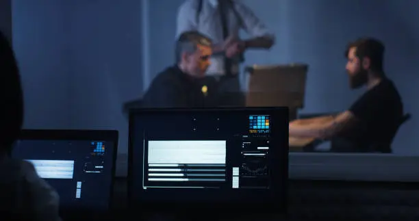 Medium shot of a female technician recording the interrogation of a criminal