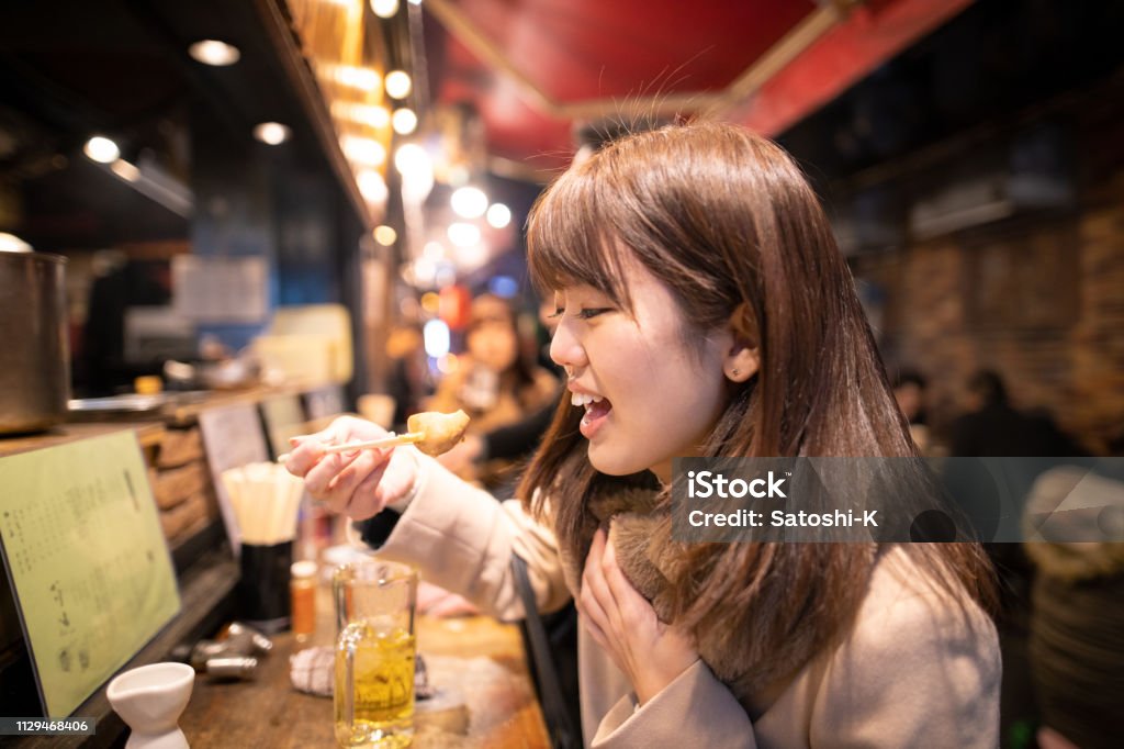 หญิงสาวกินอาหารท้องถิ่นญี่ปุ่นที่บาร์อิซากายะหลังเลิกงาน ภาพสต็อก - ดาวน์โหลดรูปภาพตอนนี้ - iStock หญิงสาวกินอาหารท้องถิ่นญี่ปุ่นที่บาร์อิซากายะหลังเลิกงาน ภาพสต็อก - ดาวน์โหลดรูปภาพตอนนี้ - Istock