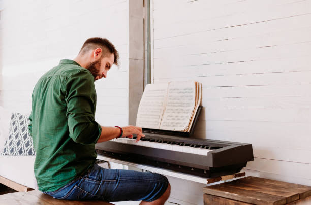 istock Young man playing electric piano at home studio 1129468726