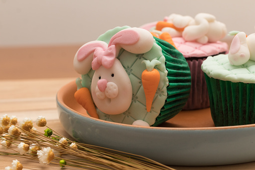 Delicious Easter cupcakes on rustic plate and wooden background