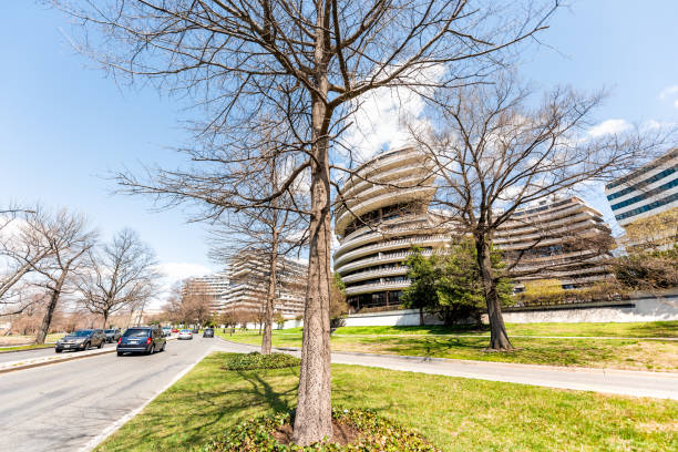 Watergate hotel building exterior in capital city residential building architecture during spring with bare trees in park Washington DC, USA - April 5, 2018: Watergate hotel building exterior in capital city residential building architecture during spring with bare trees in park hotel watergate stock pictures, royalty-free photos & images