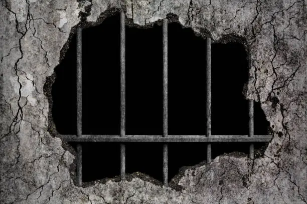 Photo of Scary background damaged grungy crack and broken concrete wall with old prison metal bars, concept of strengthen and protect with horror