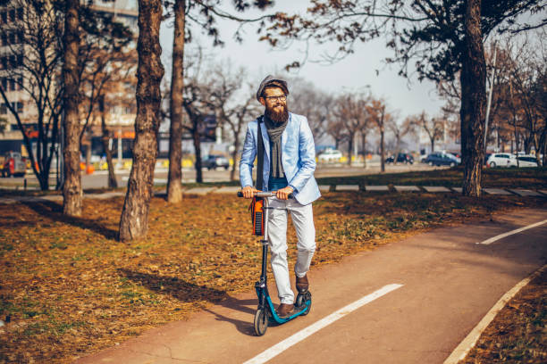 istock Young businessman with a beard smiling on kick scooter 1129472679
