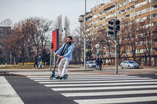 istock Young businessman with a beard smiling on kick scooter 1129473237