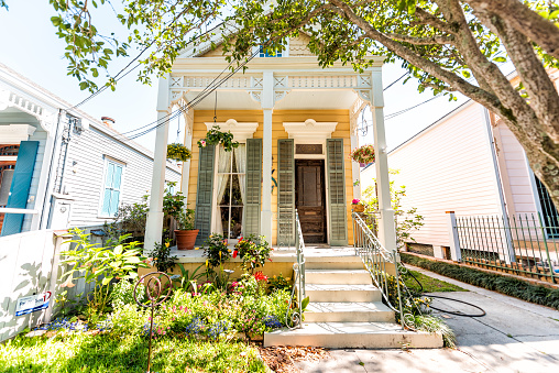 New Orleans, USA - April 23, 2018: Old street historic Garden district in Louisiana famous town city with real estate historic yellow small antebellum house