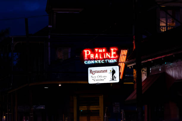 lebensmittel geschäft leuchtreklame für praline verbindung küche auf straße im französischen viertel von nola louisiana in der nacht beleuchtet - cajun food stock-fotos und bilder