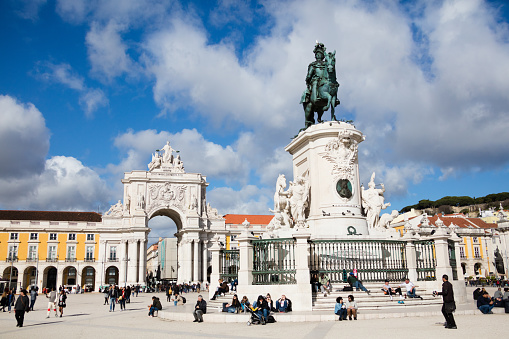 Tourists enjoying the warm sunshine in the Praca do Comercio, the landmark square overlooked by the historic Rua Augusta Arch in t Lisbon, Portugal’s capital city. In front the famous statue of King Jose I.