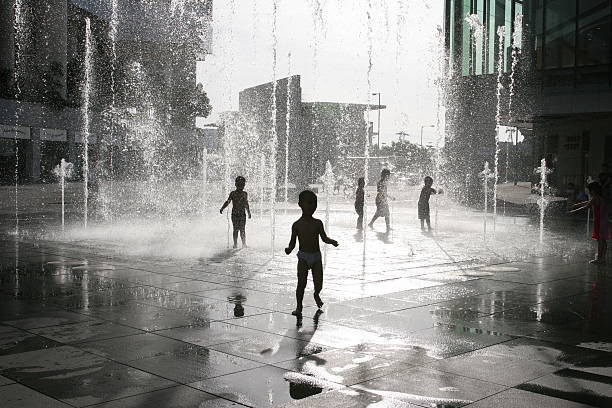 Children playing on urban fountains during the summer Children playing on a fountain noah young stock pictures, royalty-free photos & images