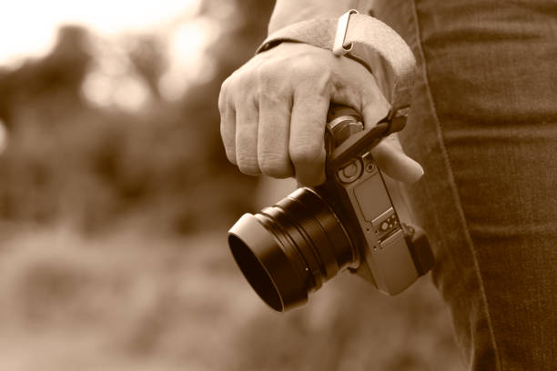 Woman hand holding digital camera in sepia tone with copy space.