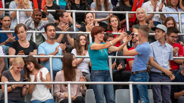 istock Woman and man in a stadium bleachers taking selfies 1129484495
