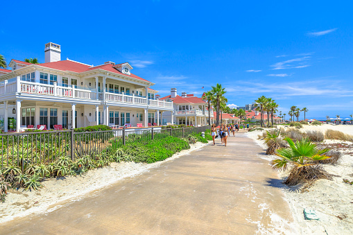San Diego, California, United States - August 1, 2018: sidewalk by beachfront cottages of Hotel del Coronado built in 1888, historic Victorian beach resort in Coronado Island, Californian west coast.