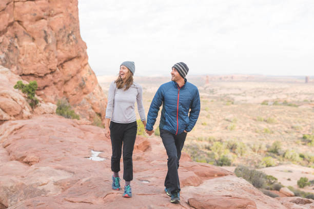 istock Young couple hold hands as they hike through the Utah desert 1129486580