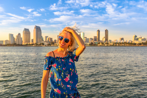 Happy tourist woman enjoying at San Diego Downtown skyline with skyscrapers in California, USA from Coronado Island. Summer holidays in america concept. Waterfront and urban cityscape in San Diego Bay