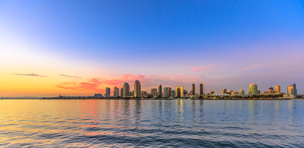 Scenic landscape with sunset colors sky of San Diego skyline with skyscrapers in San Diego Bay. Districts of Waterfront Marina skyline and urban downtown cityscape from Coronado Island.