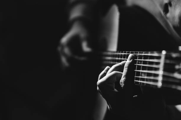 torso de hombre tocando una guitarra, blanco y negro - plucking an instrument fotografías e imágenes de stock