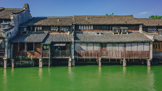 View of traditional Chinese houses by water under blue sky, in the old town of Wuzhen, China