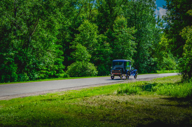 istock Blue antique car on a winding road through trees in the summer 1129493805