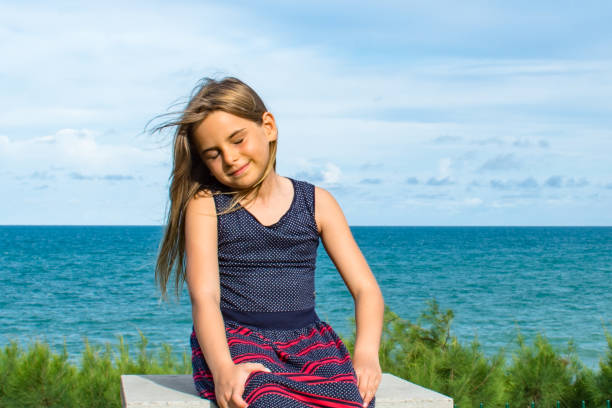 Child sitting in front of the sea on a beautiful summer day