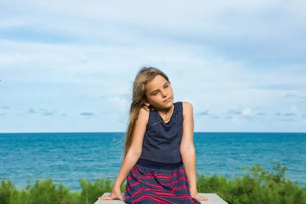 Child sitting in front of the sea on a beautiful summer day