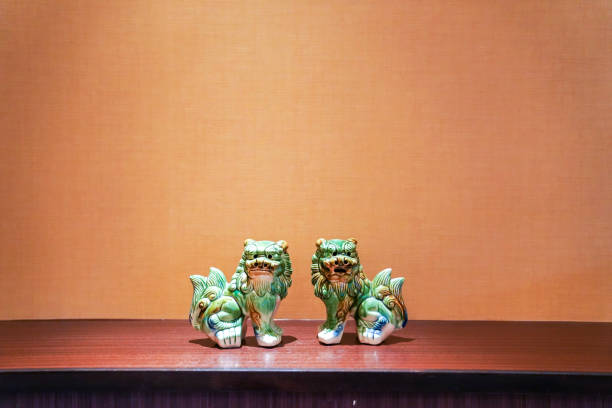 twin green seramic lion stand in the middle of frame with tungsten light.