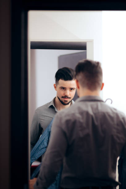 istock Man Looking in the Mirror Choosing What to Wear 1129524090