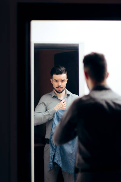 istock Man Looking in the Mirror Choosing What to Wear 1129524092