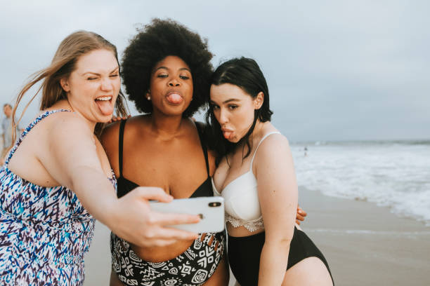 istock Beautiful curvy women taking a selfie at the beach 1129531336