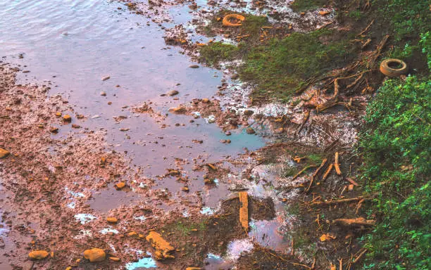 Photo of Pollution Along a River Bank in the Form of Oil, Tires, and Coal Mine Drainage.