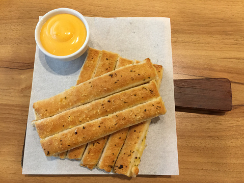 Fresh breadsticks served with dip sauce on white plate