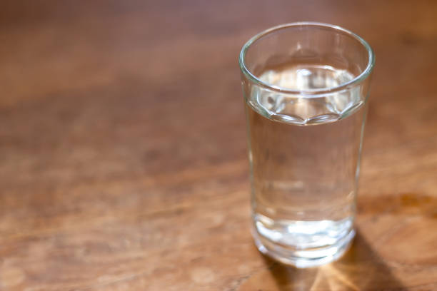 istock drinking water in the glass on wooden table with copy space. 1129544575