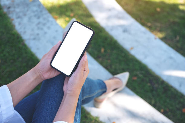 istock a woman holding black mobile phone with blank white screen 1129549192