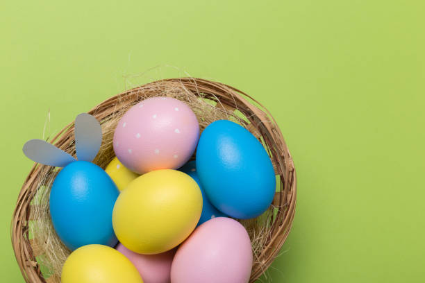 istock Colorfull easter eggs in nest on green pastel color background with space. 1129550166
