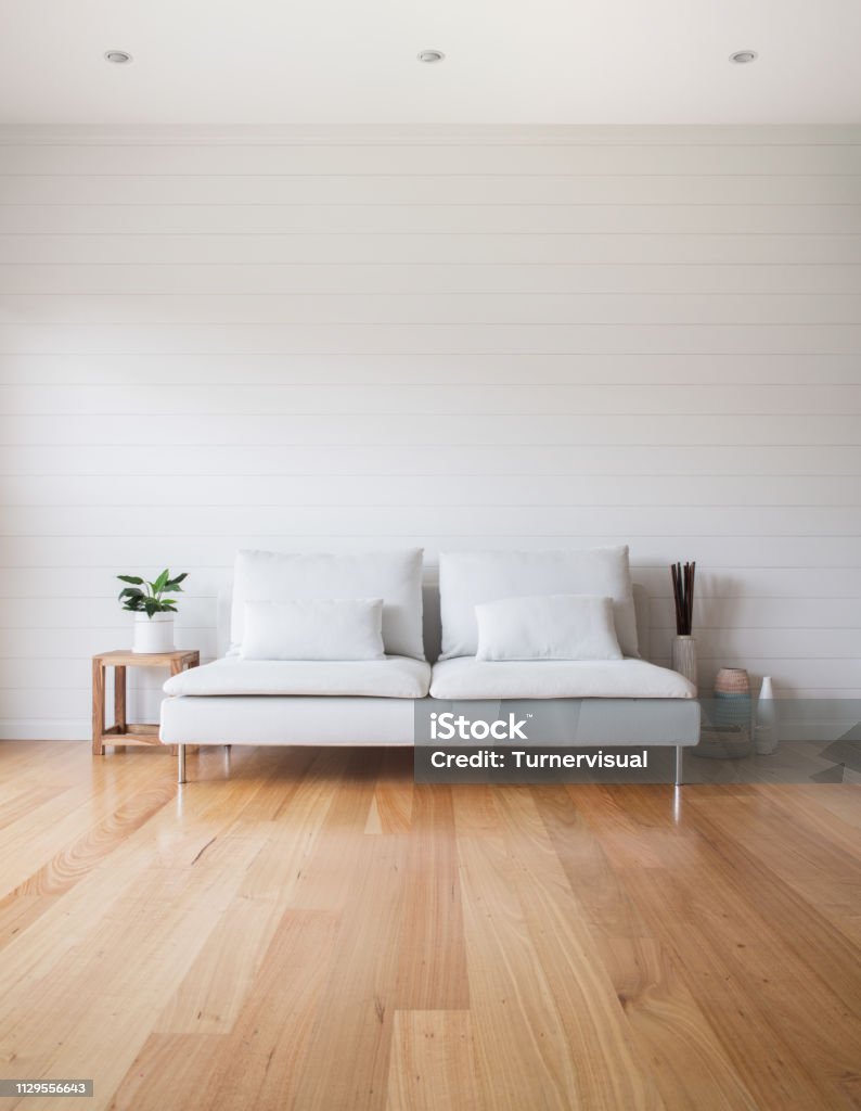 Living Room White Couch Timber Floor Stylish living room scene with white VJ panelling walls, white couch and timber floor. Lots of copy space. Living Room Stock Photo
