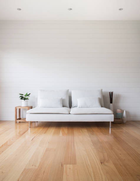 Living Room White Couch Timber Floor Stylish living room scene with white VJ panelling walls, white couch and timber floor. Lots of copy space. building storey stock pictures, royalty-free photos & images