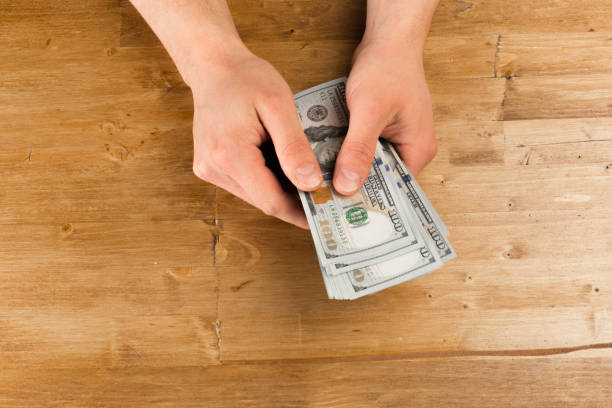 istock Man count the new us dollars on wooden table 1129559825
