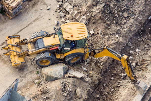 istock Yellow tractor with a bucket and back and front, digging a trench at a construction site. View from above. 1129562556