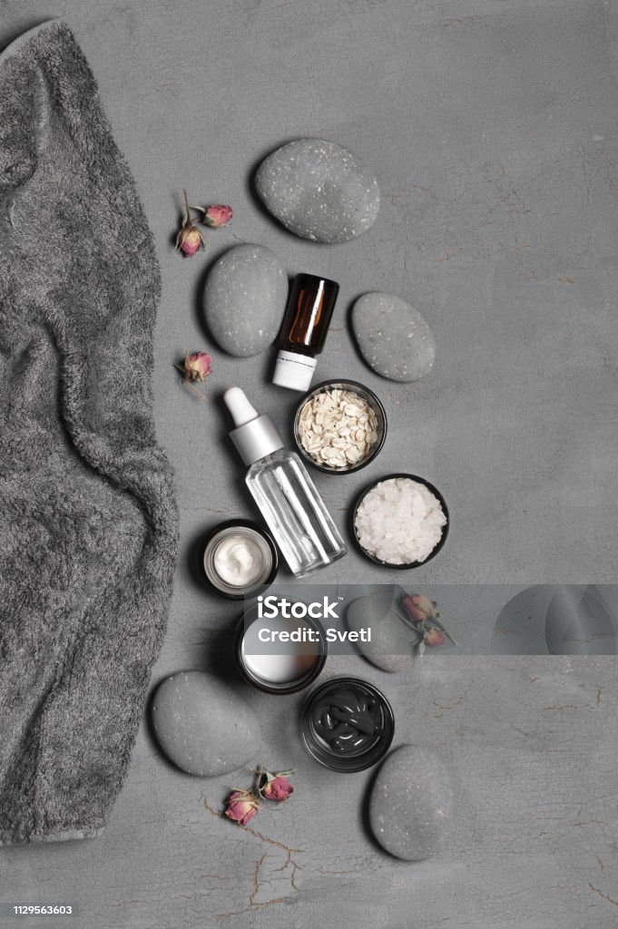 Natural organic cosmetics on grey Composition of natural organic cosmetics, pebble, terry towel and dry roses on grey background. Top view point, flat lay. Facial Cleanser Stock Photo
