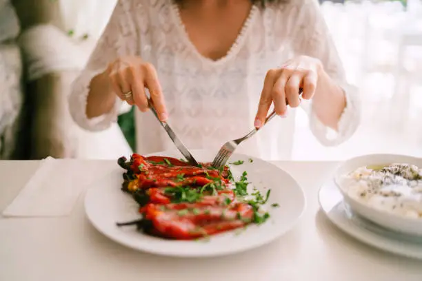 Close-up of woman eating salad of red peppers
