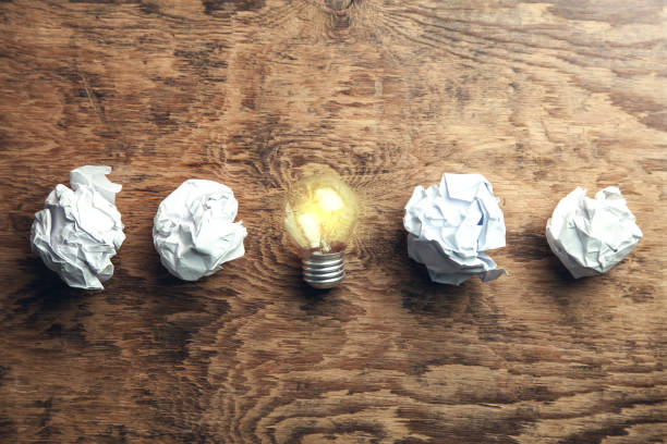istock Crumpled papers with light bulb on wooden background. Idea 1129564226
