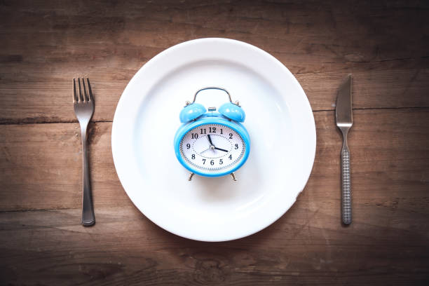 istock Alarm clock with fork and knife on the table. Time to eat 1129564237