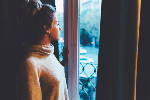 istock Beautiful woman looking out the window 1129564349