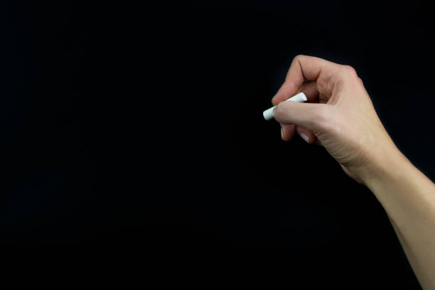 istock Hand holding chalk isolated on black background 1129565171