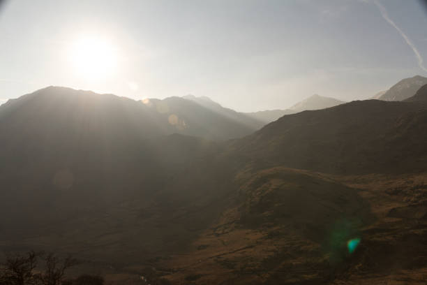 Sun setting behind a mountain peak casting rays A mountain peak in Snowdonia with the sun going down and casting sun rays. llyn gwynant stock pictures, royalty-free photos & images