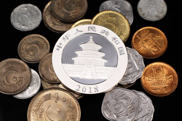 istock A  silver Chinese coin with coins from Pakistan on a black reflective background 1129565891