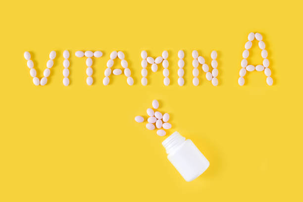 istock Vitamin A pills dropped from bottle on yellow background. Flat lay, top view, free copy space. 1129572905