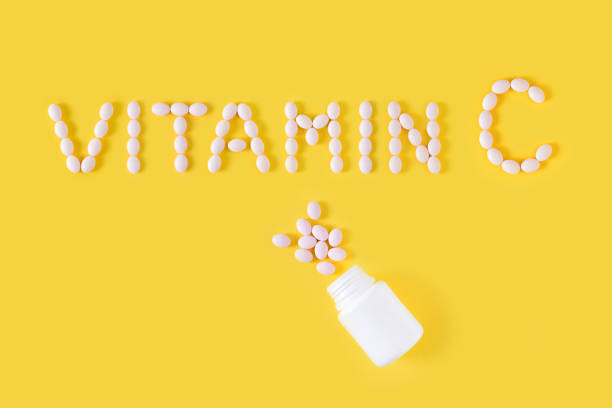 istock Vitamin C pills dropped from bottle on yellow background. Flat lay, top view, free copy space. 1129572907